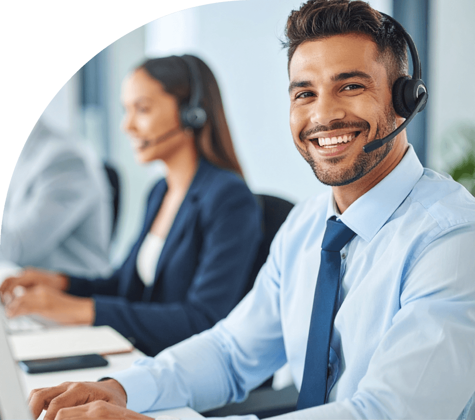aumento-fidelizacao-clientes-resultado-atendimento-crm Atendente de suporte sorrindo e utilizando um headset enquanto trabalha em um escritório corporativo, representando a segurança na tomada de decisão e o ganho de resultado no atendimento com o uso do Tactium CRM.